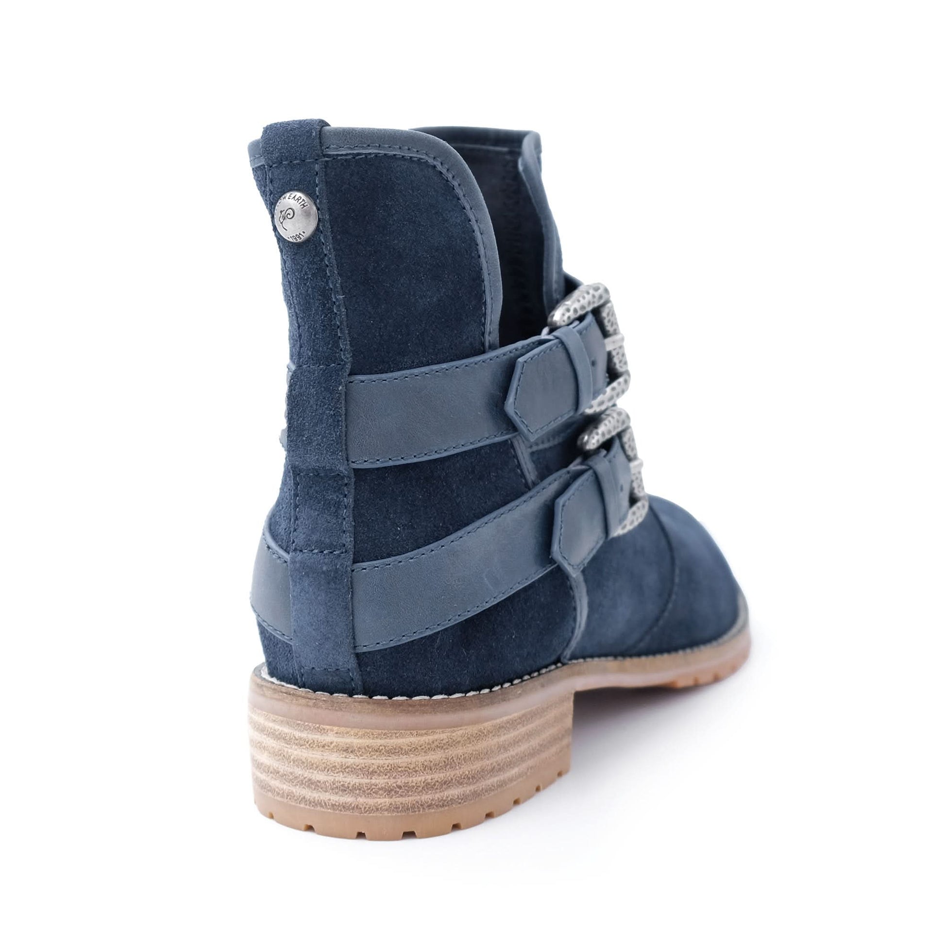 Navy blue suede ankle boot with stacked heel and decorative side straps on white background.