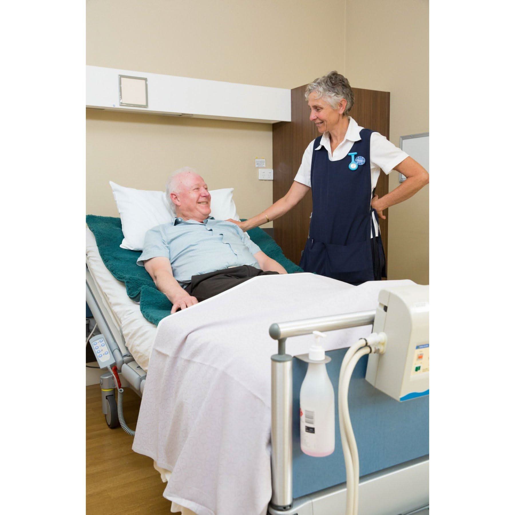 Teal wool hospital bed underlay on adjustable medical bed with patient and nurse. - Yellow Earth Australia