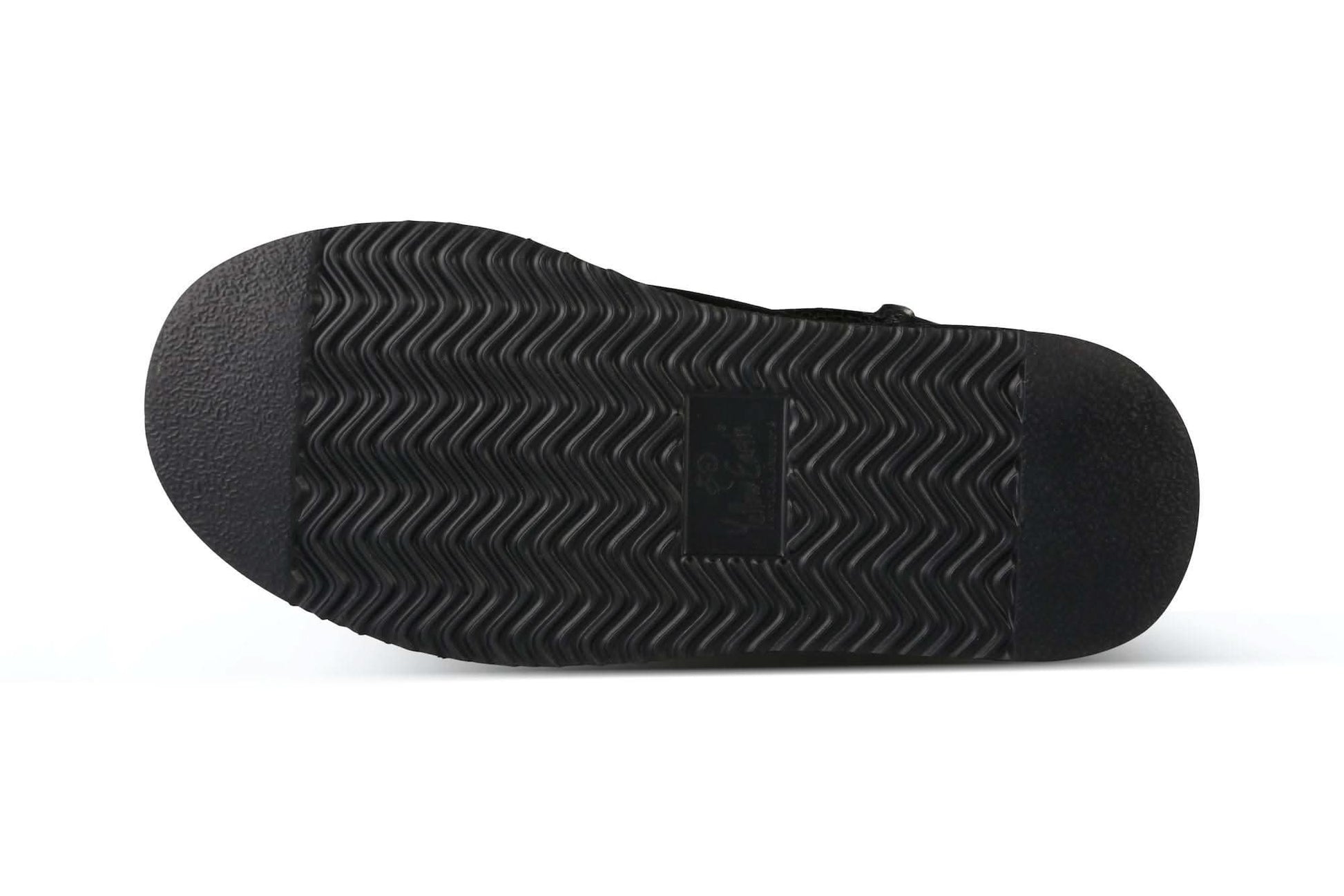 Black sheepskin slipper sole showing wavy tread pattern and textured grip, bottom view. - Yellow Earth Australia