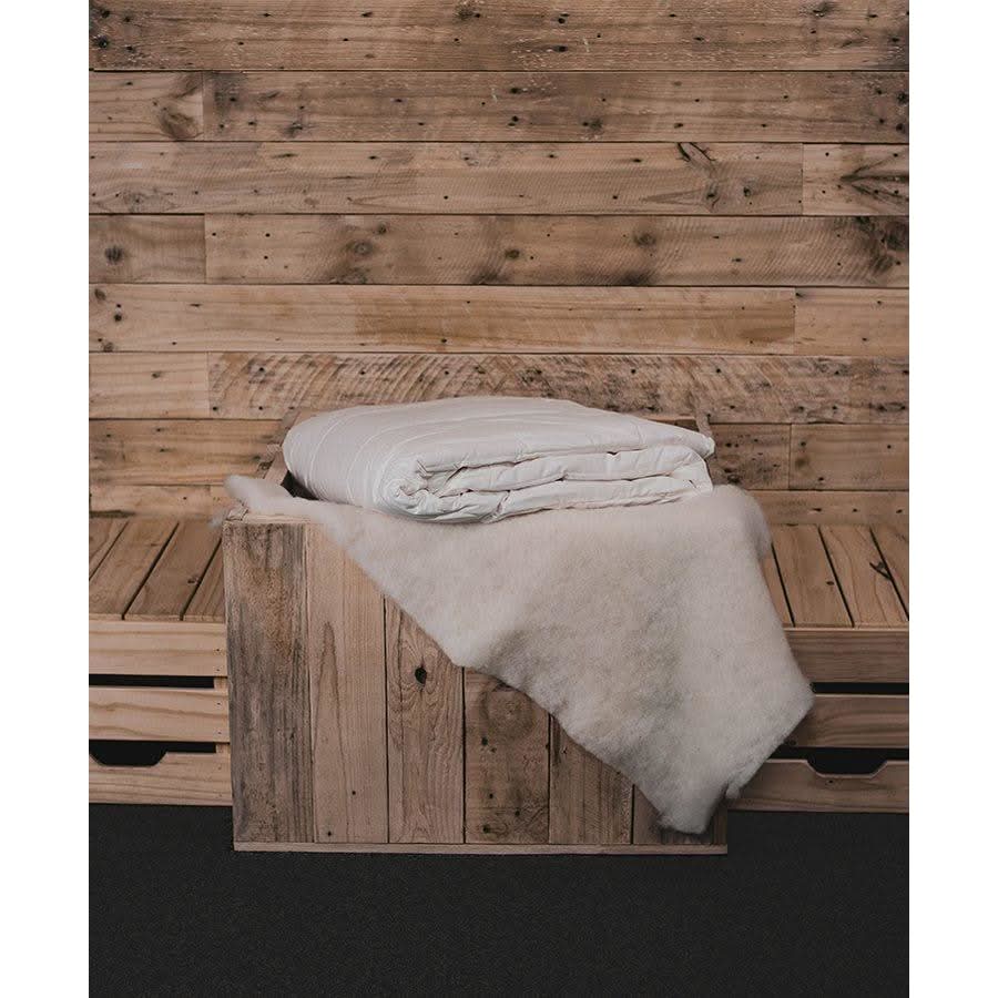 Natural wool blanket folded on wooden bench, overhead view. - Yellow Earth Australia