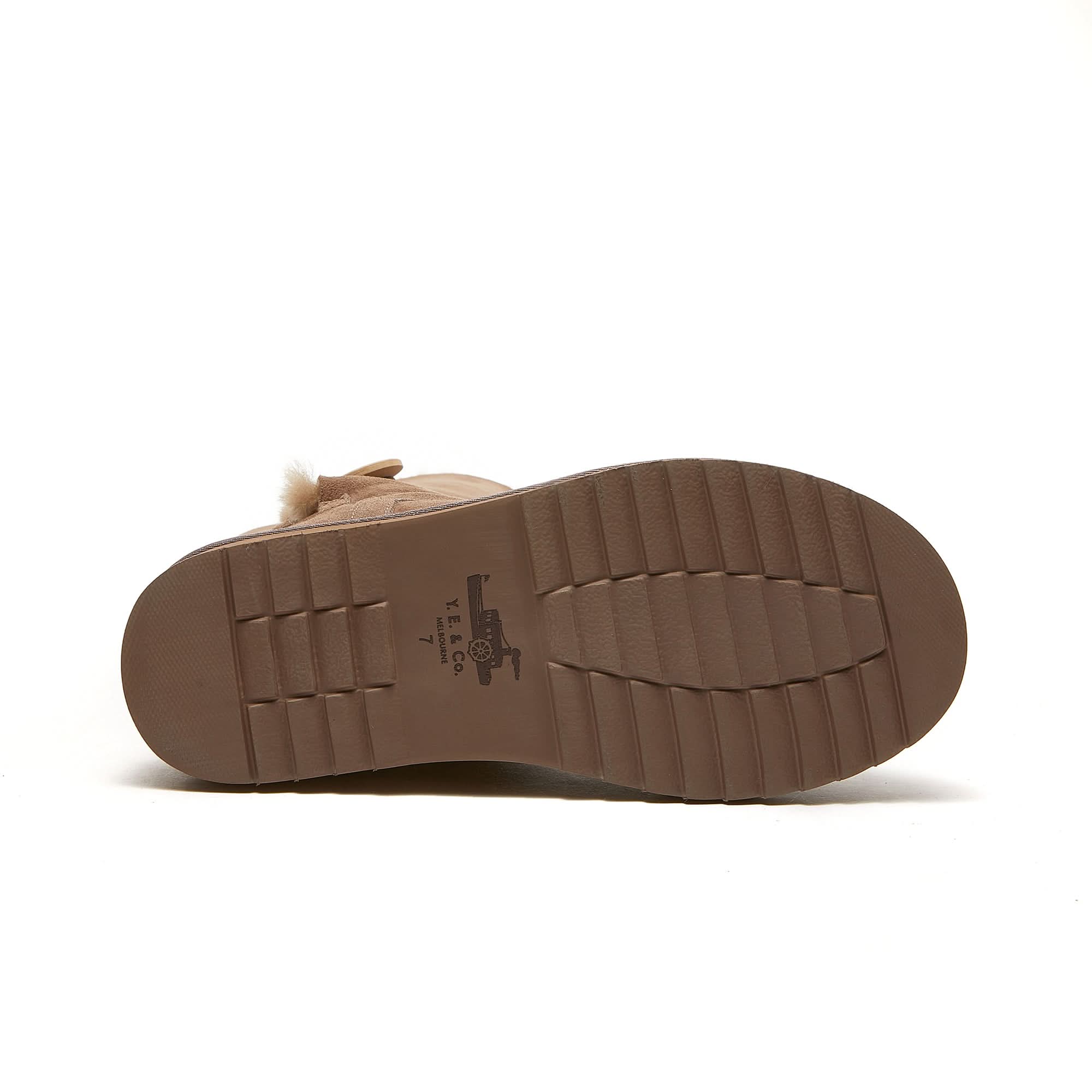 Beige sheepskin boot with treaded rubber sole shown from bottom view, size 7.