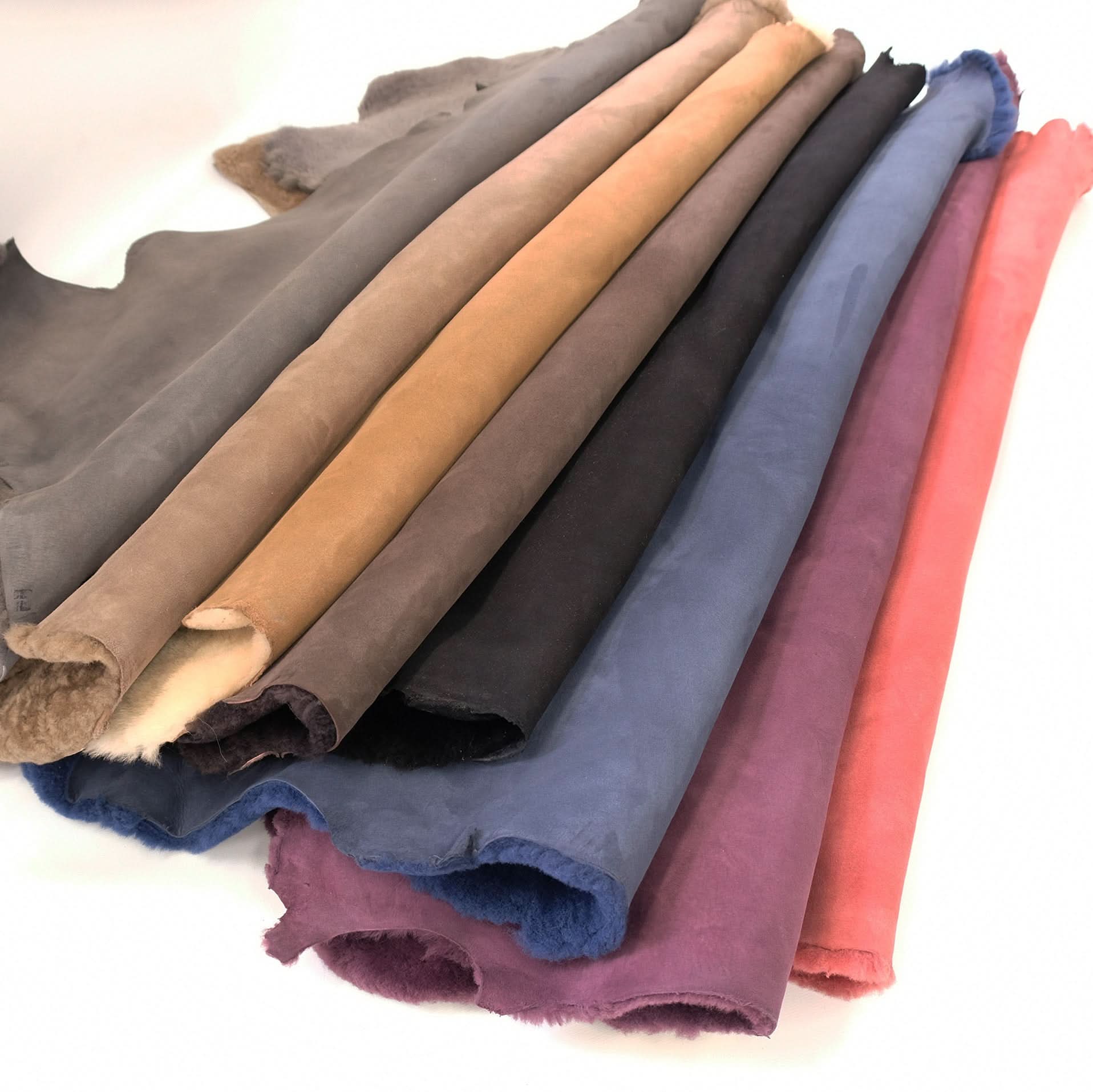 Rolled sheepskin wool swatches in neutral and jewel tones showing texture and colour range. - Yellow Earth Australia