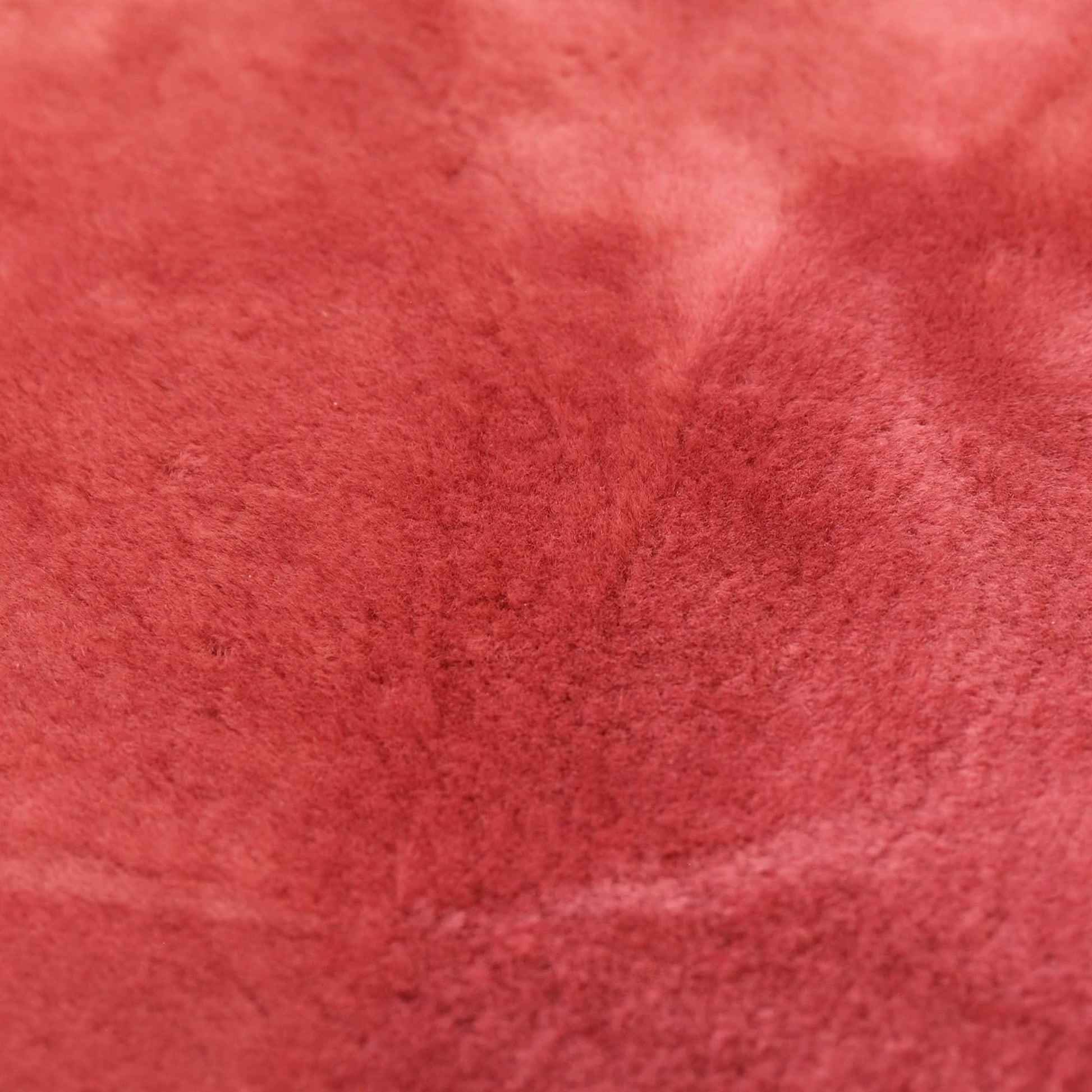 Red wool sheepskin texture close-up showing soft fluffy pile surface. - Yellow Earth Australia