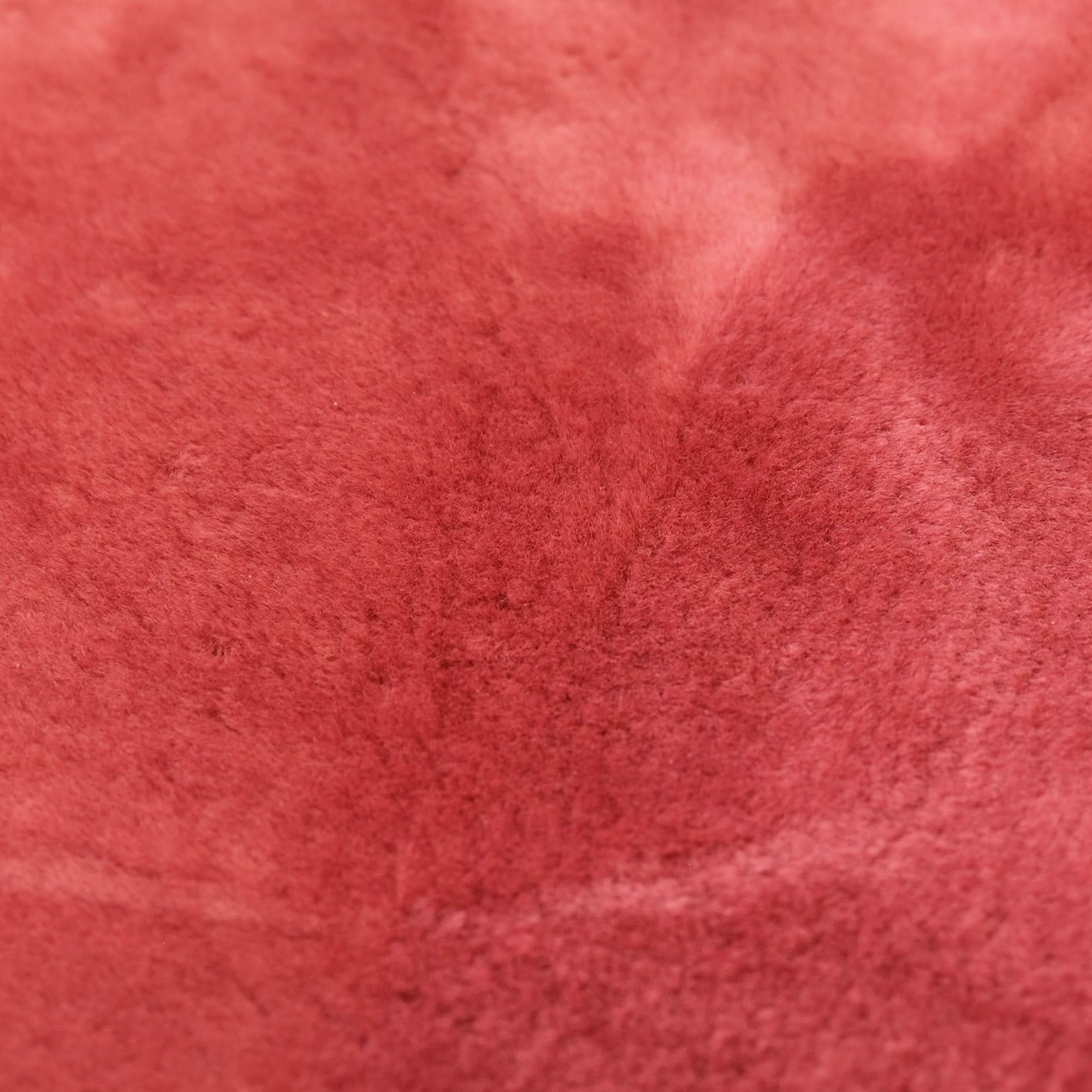 Red wool sheepskin texture close-up showing soft fluffy pile surface. - Yellow Earth Australia