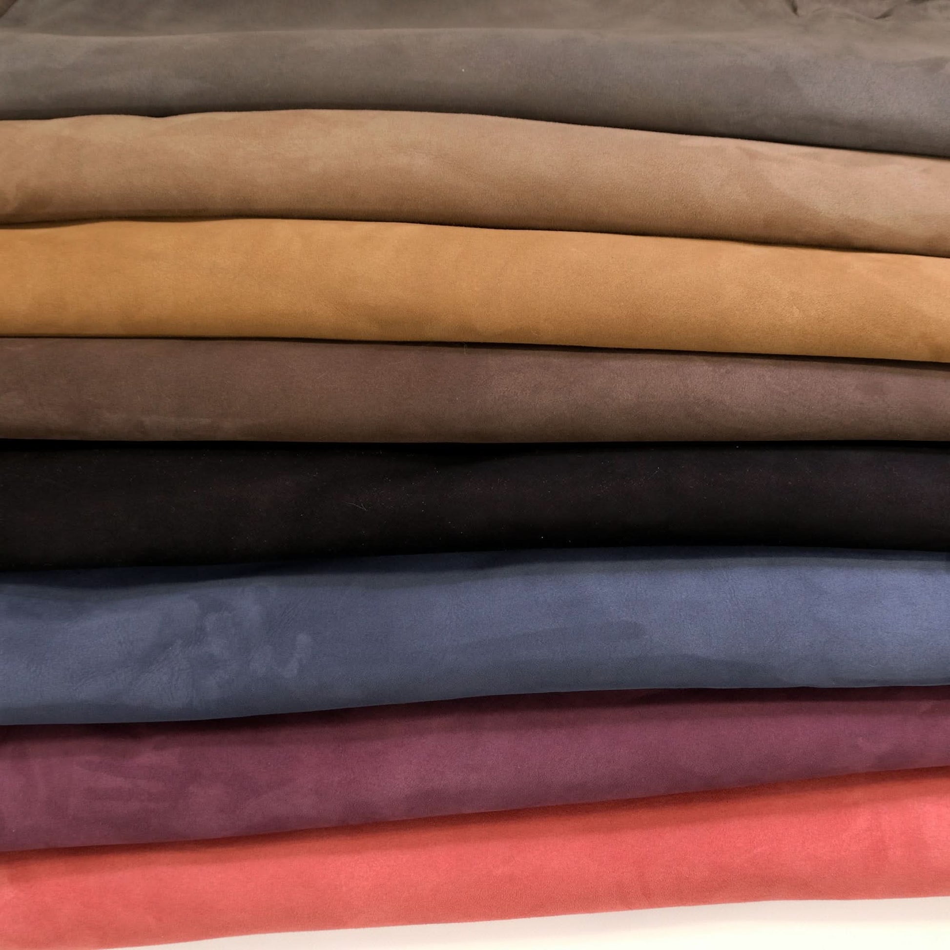 Stacked wool fabric swatches in neutral and jewel tones showing soft suede texture. - Yellow Earth Australia
