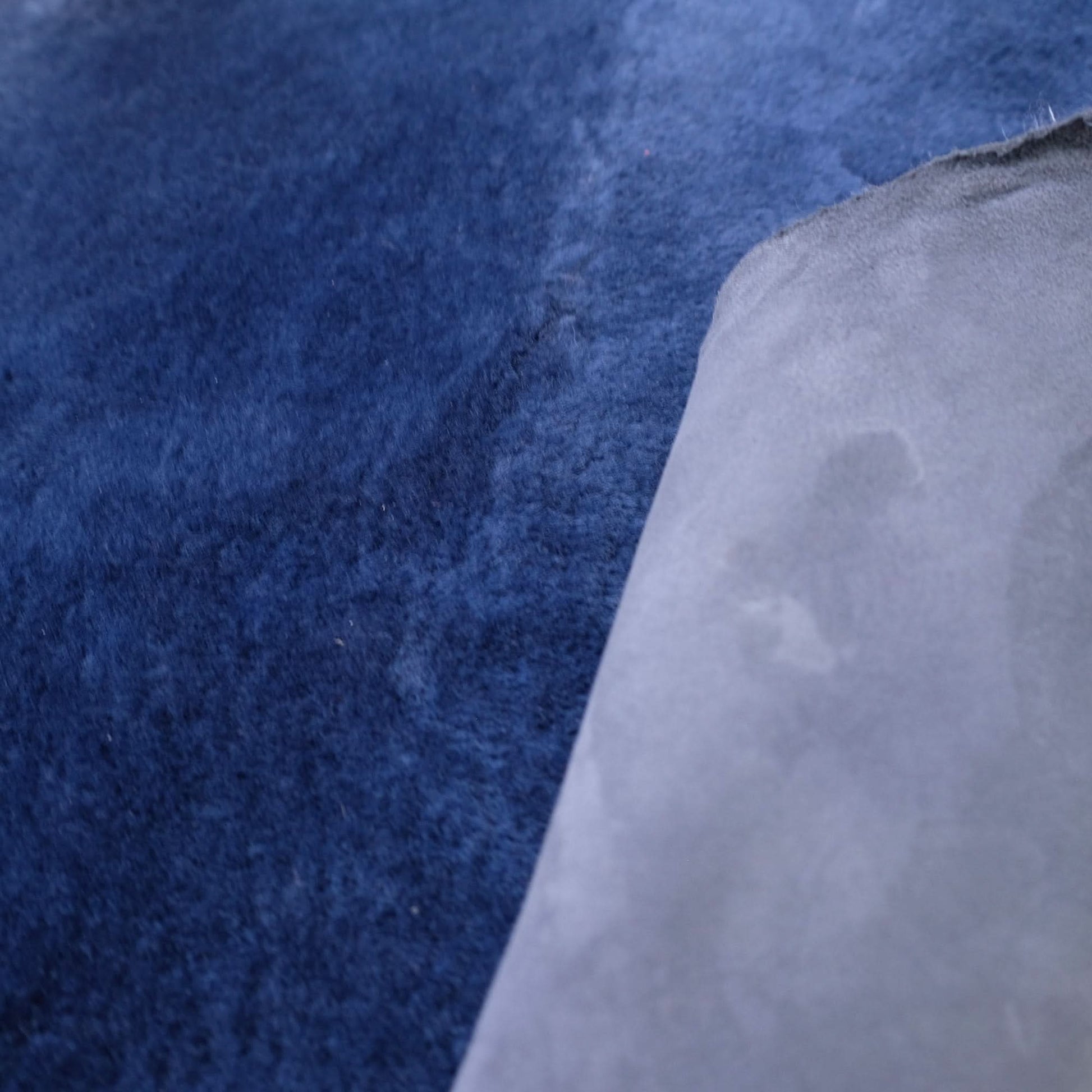 Close-up of navy blue wool felt showing soft textured surface with white backing layer. - Yellow Earth Australia
