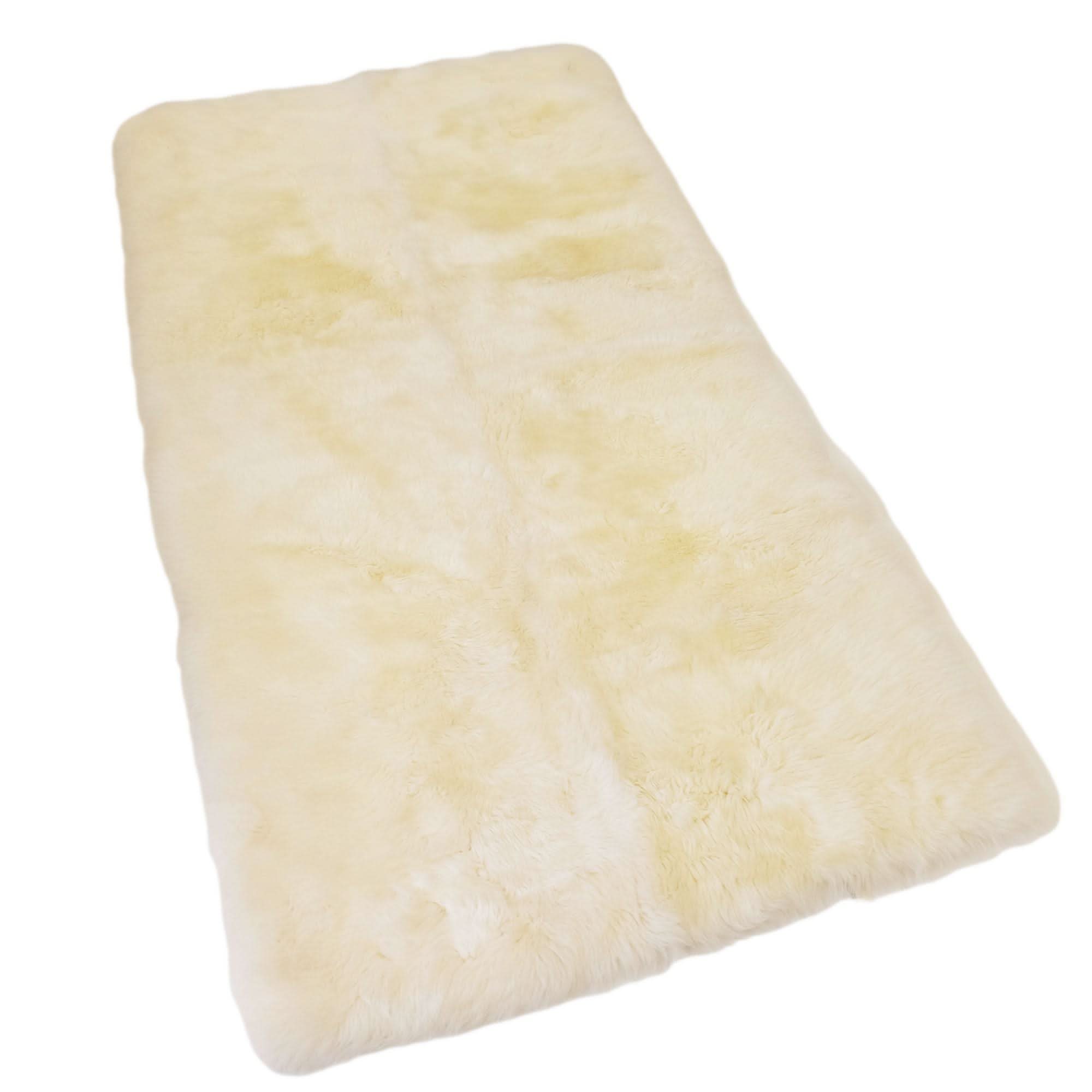 Cream sheepskin rug with soft wool fleece displayed at angle on white background. - Yellow Earth Australia