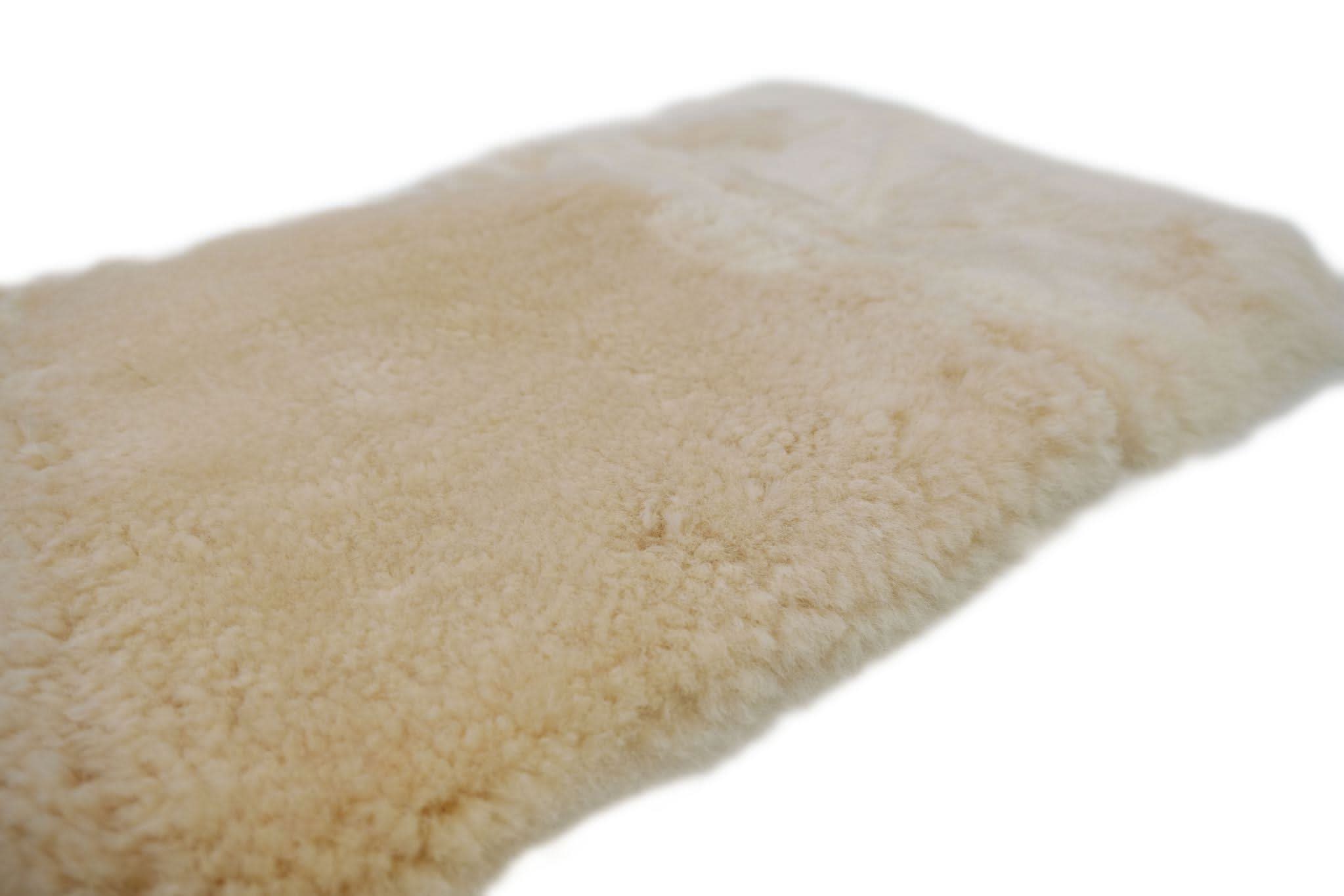 Cream sheepskin rug with soft wool pile viewed from above angle. - Yellow Earth Australia
