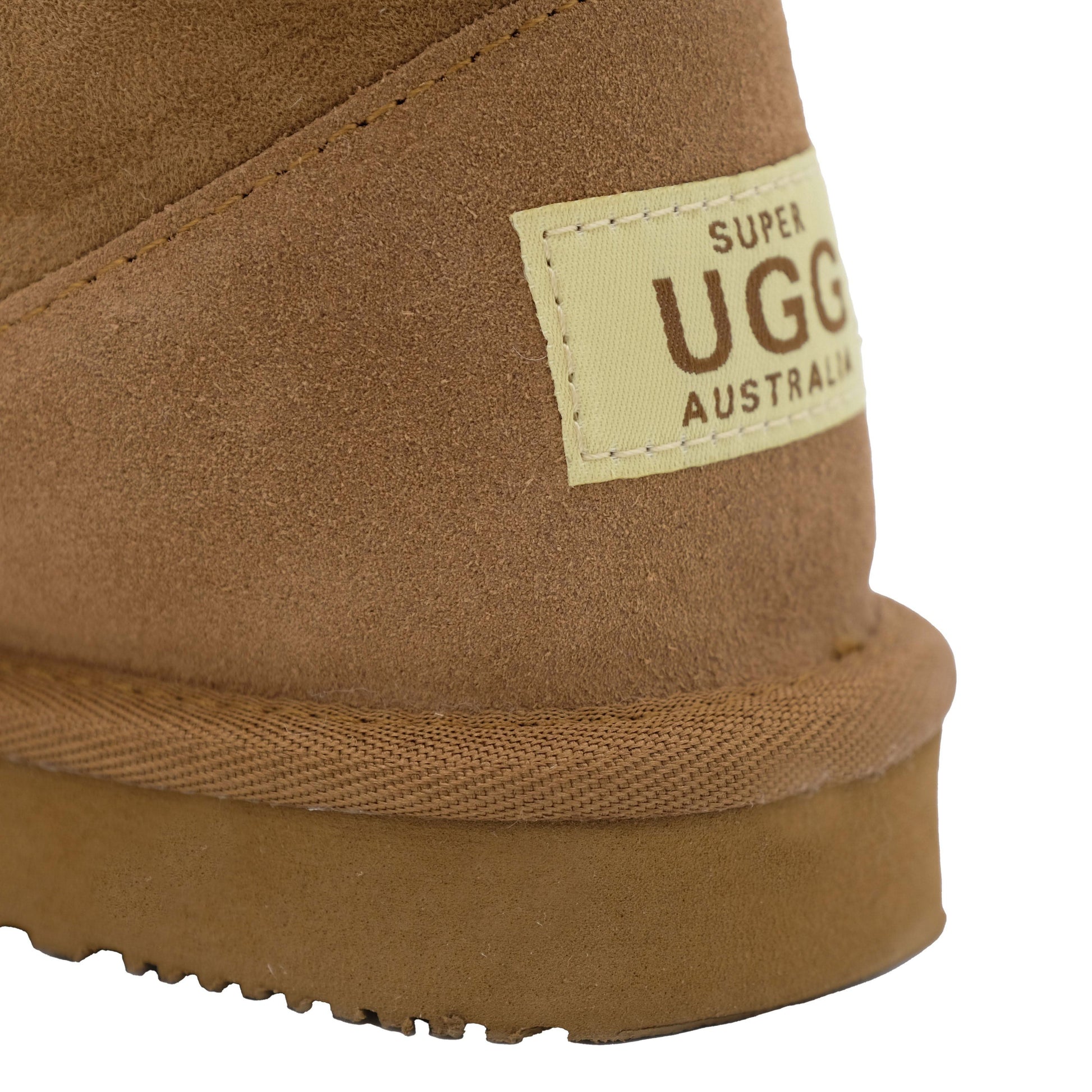Tan suede sheepskin boot with cream label, close-up of side and sole detail. - Yellow Earth Australia